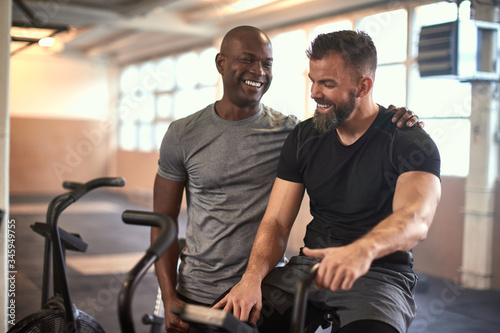 Two men laughing after exercising on stationary bikes photo