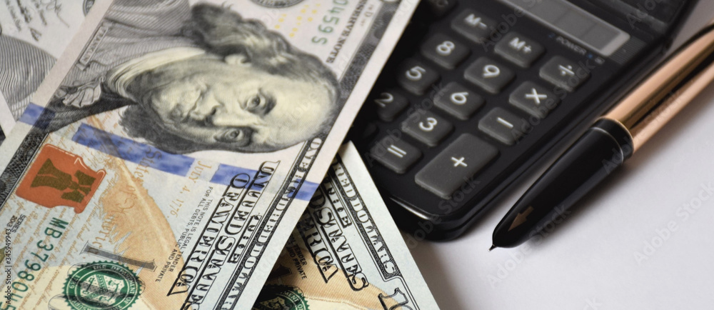 a few dollar bills, banknotes on a white background, with a golden pen and calculator, business concept a few dollar bills, banknotes on a white background, with a golden pen and calculator, business concept