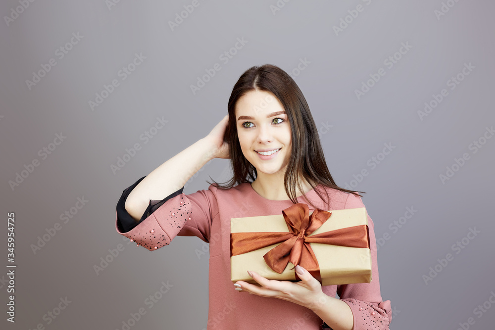 Girl in a pink dress with gifts on the eve of the holiday. Blank for advertising, a man receives gifts on a gray background,