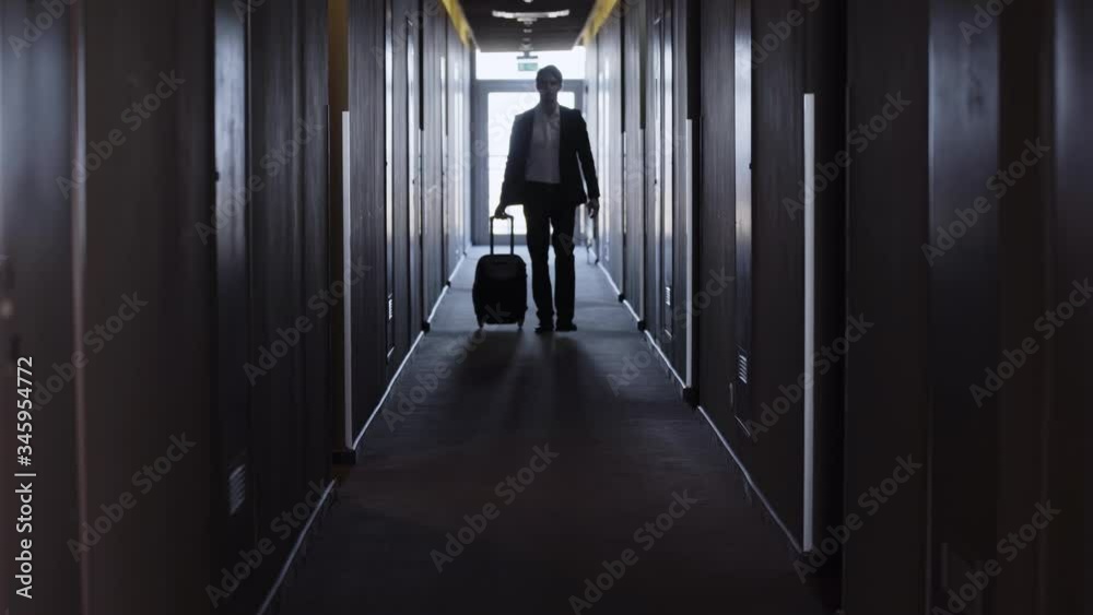 businessman with suitcase walking along hotel corridor businessman with suitcase walking along hotel corridor