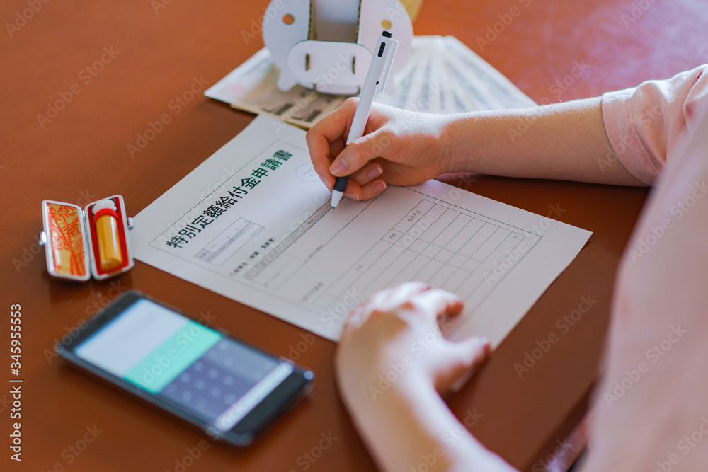 Japanese woman writing document application for getting special cash payment Japanese woman writing document application for getting special cash payment