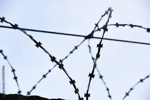 Fence with barbed wire against a blue sky background. Security concept, forbidden territory, entry prohibited/no entry