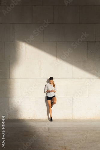 Young stylish professional woman on her coffee break texting on smartphone outside.