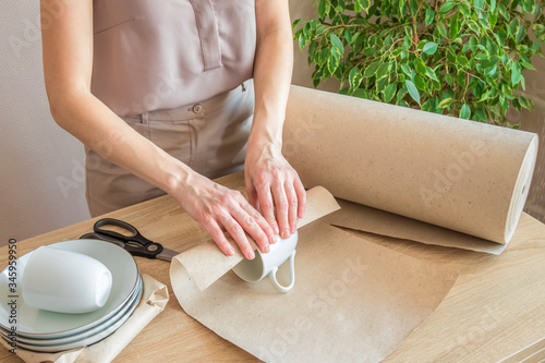 a young girl wraps porcelain dishes for sale in an online store. online store of kitchen utensils