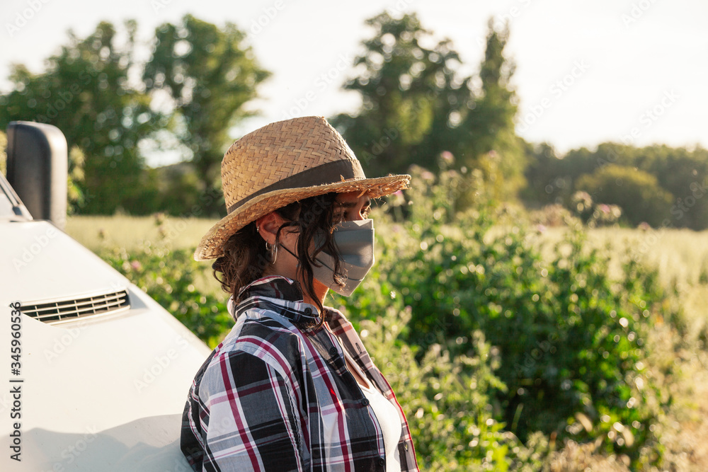 Young farmer woman with straw hat and surgical mask