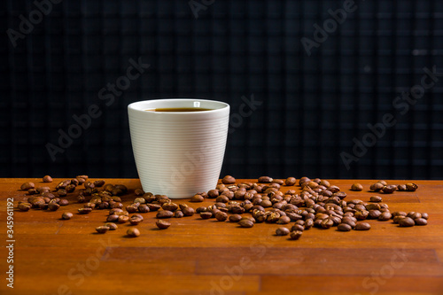 A cup of coffee and roasted coffee beans on a wooden table