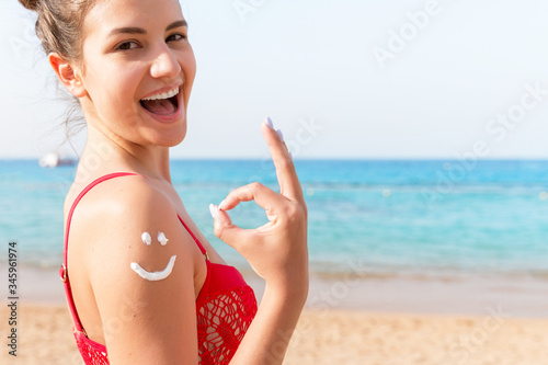Sun cream over tanned woman's shoulder in the shape of smiling face
