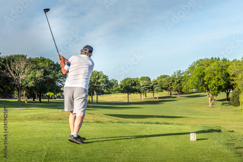 Man teeing off in the tee box, playing golf