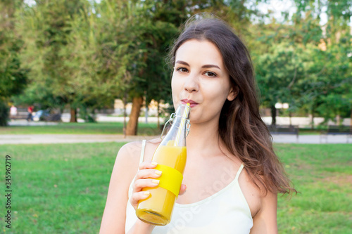 Closeup of beautiful girl with a bottle of fresh juice. Healthy woman is posing with lemonade. Diet nutrition with detox juice