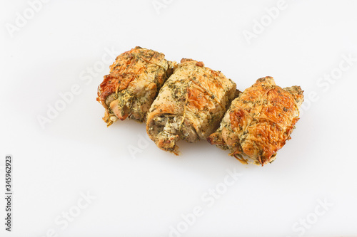 Chicken roll in grid decorated lettuce leaf isolated on wooden background. Fresh meat product whole and partly sliced. Chicken ham, and slices of tasty chicken meat. Natural product from organic farm.