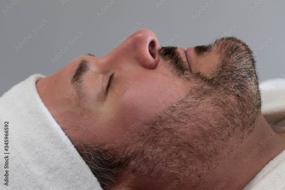 Obraz premium A side profile of a Caucasian man relaxing at a spa. He is ready to have a beauty skincare treatment and facial.