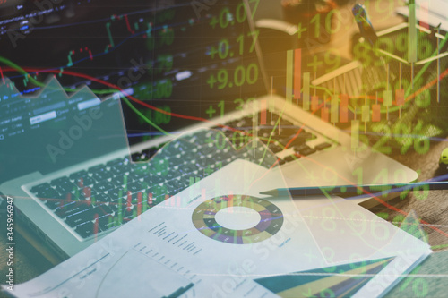 Double exposure of stock market graph and business desk for finance investment and business. Investment and economic concept