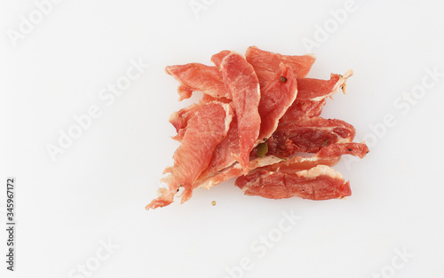Meat smoked jerky - raw meat sausage meat. Close up view on tasty sliced Chicken basturma on parchment on a wooden board on a wooden background in a composition with spices. Beer snack. Pastirma