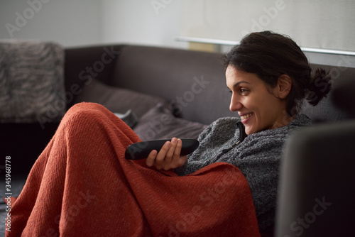 Woman watching TV sitting on her couch at home.