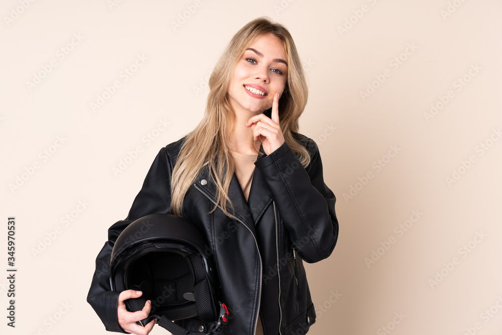 Russian girl with a motorcycle helmet isolated on beige background smiling with a happy and pleasant expression