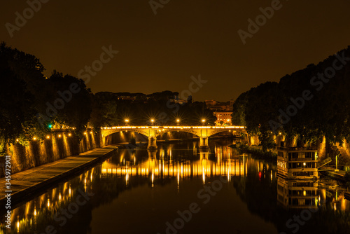 Vista nocturna de un puente sobre el rio Tiber en Roma photo