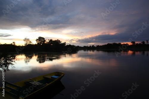 Landscape of Amazon jungle river with floating boat during sunrise in Brazil