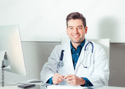 Portrait of young smiling doctor sitting in medical office
