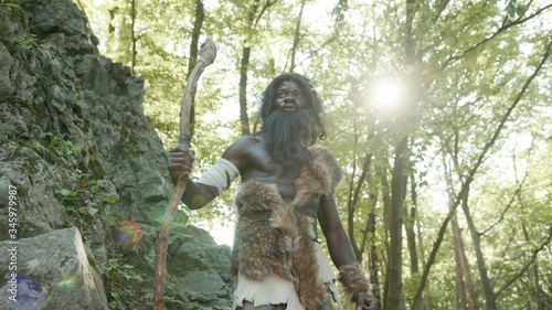 Εκτύπωση καμβά Proud african leader of prehistoric cro-magnon tribe hunting for food in mountain landscape deep forest