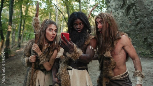 Obraz na płótnie Ancient neanderthals tribe people hunting in forest looking at miracle smartphone rejoicing with future technology growling like gorillas