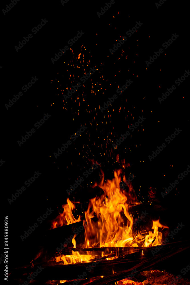 Obraz premium A campfire with a large log and rising sparks on black
