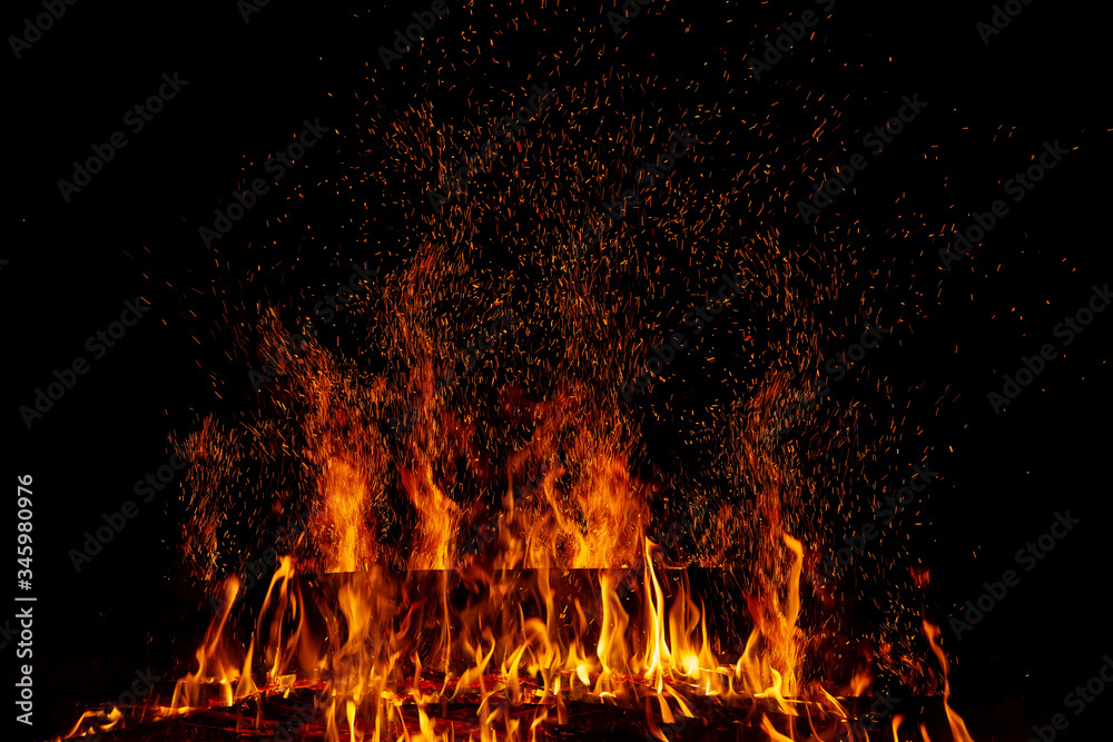 A burning log in a fire with multiple sparks in the night darkness A burning log in a fire with multiple sparks in the night darkness