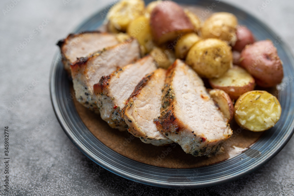 Roasted pork with spices and Parmesan roasted baby potatoes. Close up on a plate. Roasted pork with spices and Parmesan roasted baby potatoes. Close up on a plate.