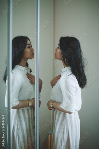 Asian girl is looking herself in the mirror