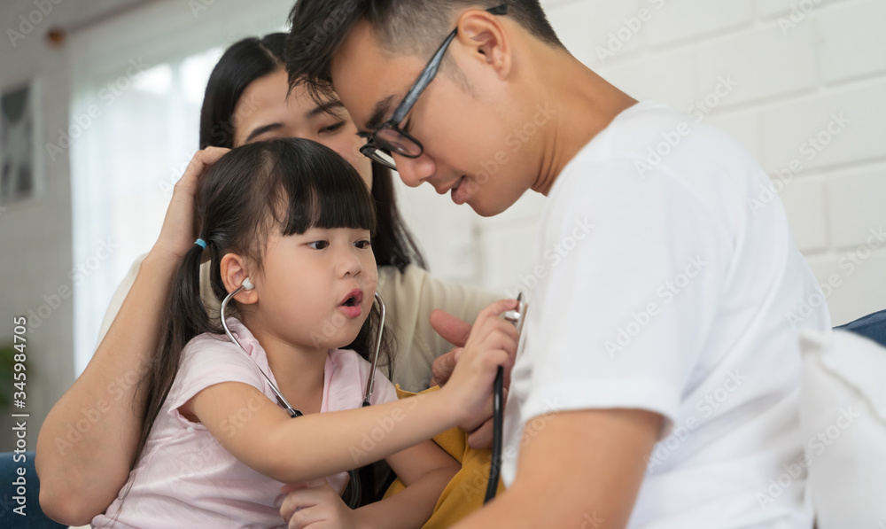 Daughter playing as doctor with family holding stethoscope listening to father patient at home Daughter playing as doctor with family holding stethoscope listening to father patient at home