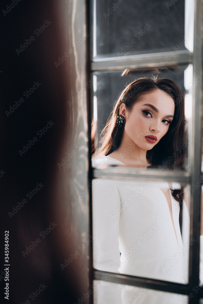 a beautiful bride in a white glittering wedding dress with brown hair poses in a photo Studio a beautiful bride in a white glittering wedding dress with brown hair poses in a photo Studio