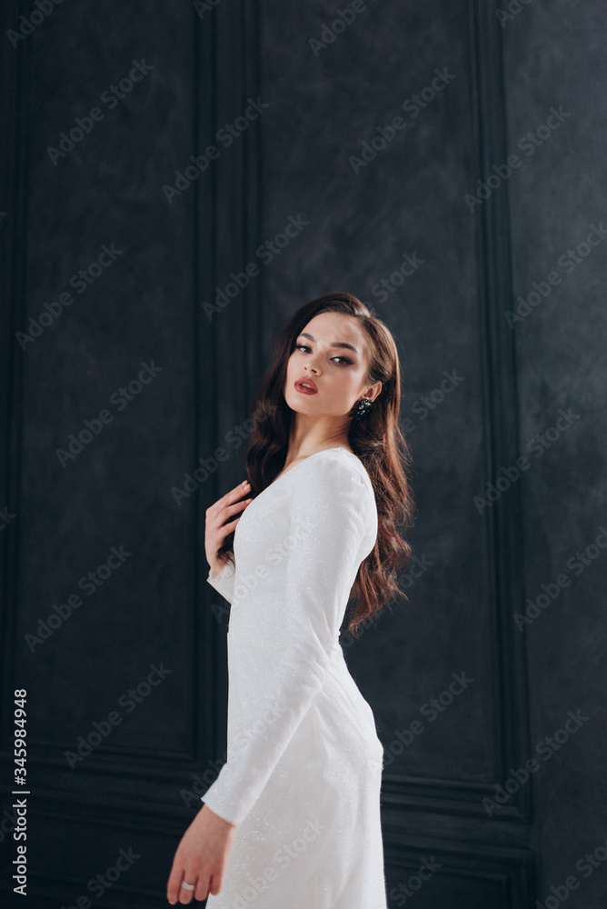 a beautiful bride in a white glittering wedding dress with brown hair poses in a photo Studio a beautiful bride in a white glittering wedding dress with brown hair poses in a photo Studio