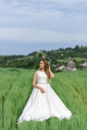 Close-up portrait of a beautiful bride. Woman posing in a green wheat field.