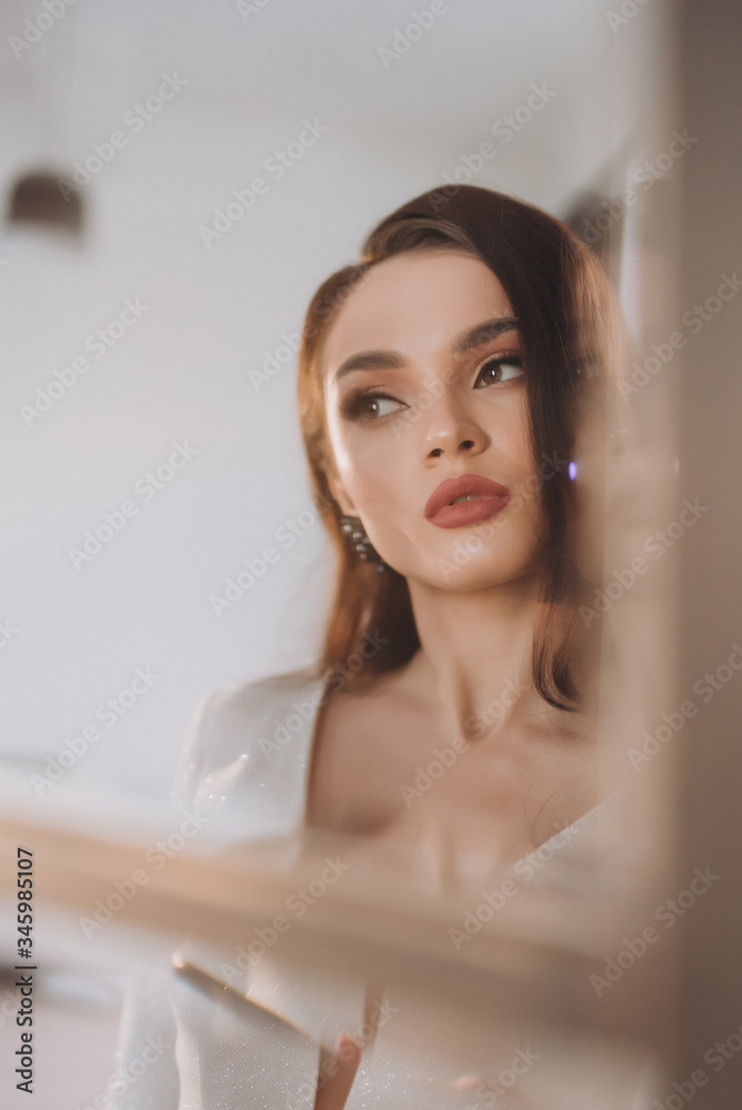 a beautiful bride in a white glittering wedding dress with brown hair poses in a photo Studio