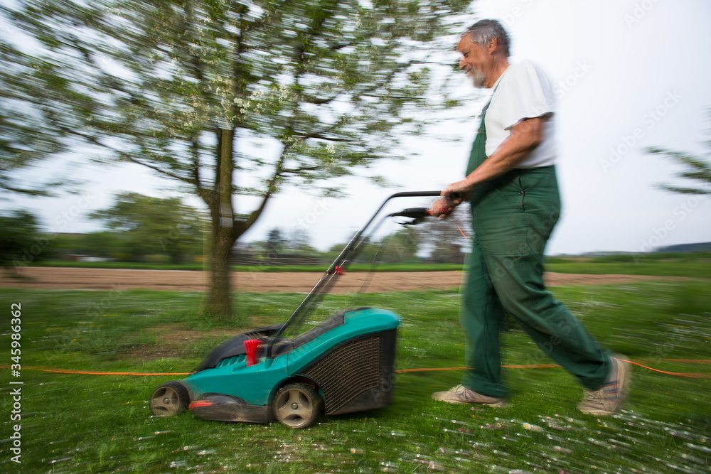 Gardener mowing the lawn - motion blurred image (color toned image) Gardener mowing the lawn - motion blurred image (color toned image)