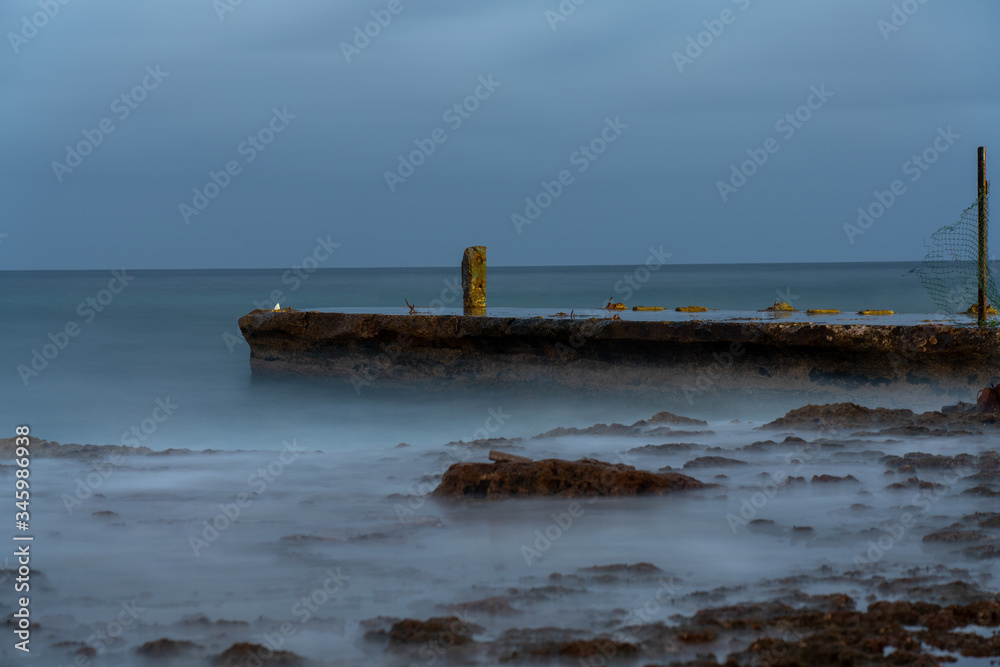 Low exposure photo of a small pier at dusk on a Havana coast. Cuba