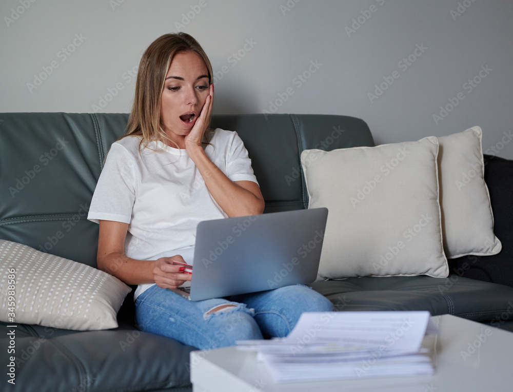 Debt worried young female with laptop seating on the couch Debt worried young female with laptop seating on the couch