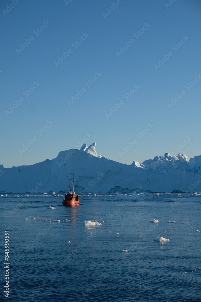 Obraz premium Telephoto shot of boat among the icebergs in Disko bay Ilulissat
