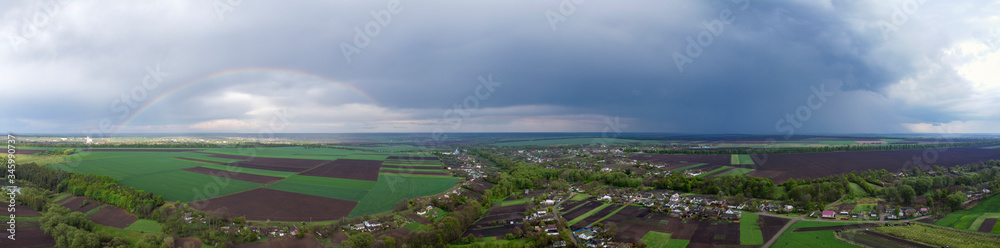 Landscape panorama of the village over which the rain passed and a rainbow appeared.