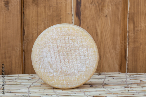 whole round partmesan or pecorino cheese head isolated on wooden background. Fresh dairy product, healthy organic food. Delicious appetizer. photo