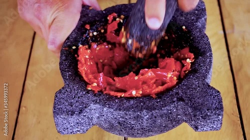Preparing red hot chilli peppers in a morter for a hot sauce