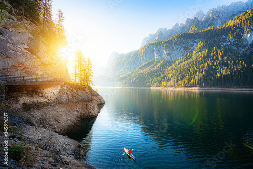 Scenic autumn sunrise scenery with adventurer kayaking in idyllic mountain lake in the Alps in fall, Austria
