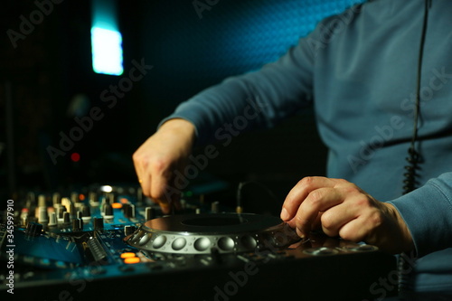 dj's hand is mixing tracks at party in night club. disc jockey playing music on the modern turntable close up