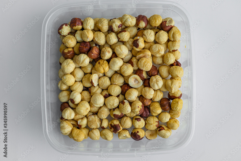 Top closeup view of delicious crispy snacks such as dry fried hazelnuts which are stored in plastic transparent container Top closeup view of delicious crispy snacks such as dry fried hazelnuts which are stored in plastic transparent container