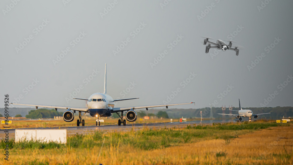 Fototapeta premium Drone flying near commercial jet airplanes taxiing on international airport. Aviation hazard due to possible collision causing flight disruption and delay - composite image