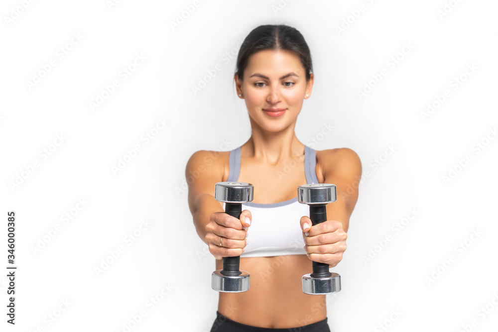 The girl holds two identical dumbbells in her hands. Focus on the Dumbbell The girl holds two identical dumbbells in her hands. Focus on the Dumbbell