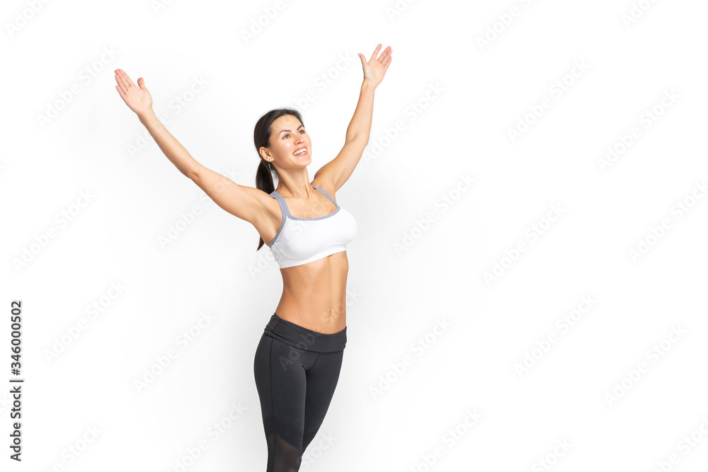 a young athletic woman smiles and raises her hands up. Isolated over white background. Vertical photo a young athletic woman smiles and raises her hands up. Isolated over white background. Vertical photo