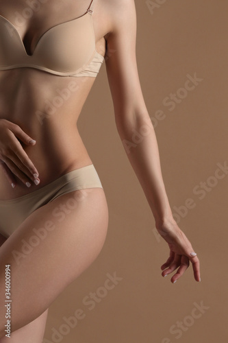 Slim young woman dancing in lingerie on a beige background