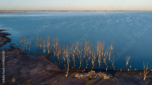 Sunrise on the horizon with the glow reflected in the creek, flooded trees in Epecuen, near Carhue, Buenos Aires Province, Ar gentina. photo