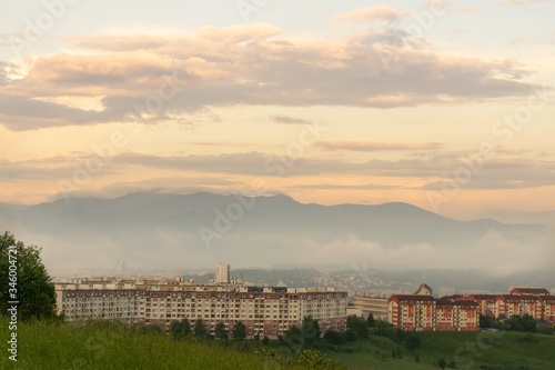 Sunrise and sunset, beautiful clouds over the meadow, hills and buildings in the town. Slovakia