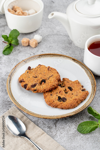 American chocolate chip cookies on rustic plate with sugar, mint and teapot on background